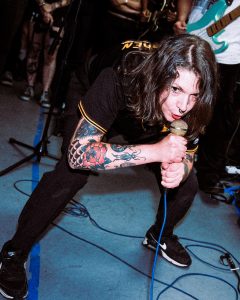 a person with tattooed arms crouching down over a microphone