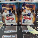 This picture depicts two boxes of Topps 2024 baseball trading cards, still sealed in shrink wrap marked with the Topps logo.
