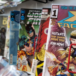 Marvel and DC comic books on a store shelf. The book in front is titled "X Factor."