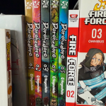 A collection of manga standing on its side on a shelf. The titles read "Dorohedoro" and "Fire Force."