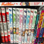 A selection of manga standing on its side on a shelf. The spines read "Fire Force," "Food Wars!" "Hell's Paradise," and "Gamera: Code Thyrsos."