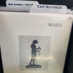 A vinyl record cover in a record flip bin by the artist Maria. The record has a small tag with the price $10. There are two tab dividers visible in the bin that read "805 Artists - LP's New" and "Yay! Records."