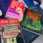 Several books lying on a table. The titles read "How to Kill a Guy in Ten Dates" by Shailee Thompson, "Videotapes from Hell" edited by Stephen Jones with Forward by Joe Dante, and an R. L. Stine "Fear Street" collection.