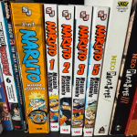 A collection of Manga books on their side on a shelf, including Naruto and Neo Parasyte