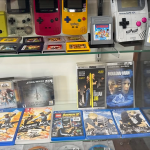 A glass display case containing a LEGO Nintendo Gameboy, several PSVita games, several Gameboy Colors (including a Pokemon edition), and a few PSP games.