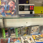A glass display case containing a Gameboy Color, a Nintendo DS, Playstation games in cases, and several PS4 and Nintendo Switch games
